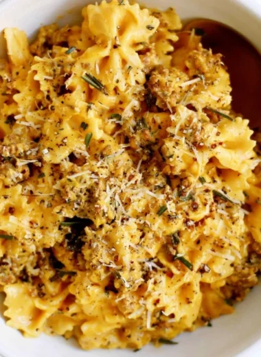 Creamy pumpkin pasta served in a bowl with herbs and cheese on top.
