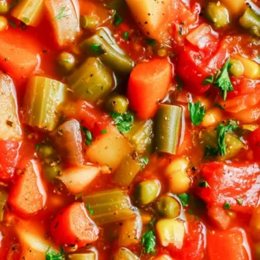 A bowl of hearty vegetable soup with colorful vegetables and herbs