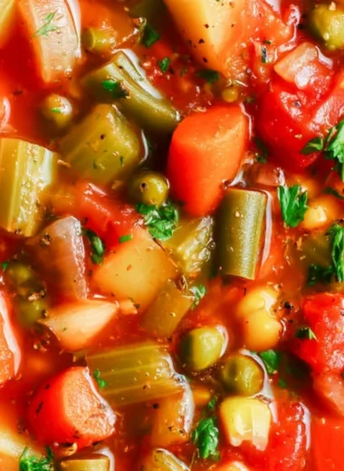 A bowl of hearty vegetable soup with colorful vegetables and herbs