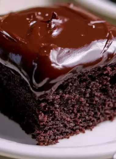 Wacky Chocolate Cake topped with sprinkles and chocolate drizzle on a rustic plate.