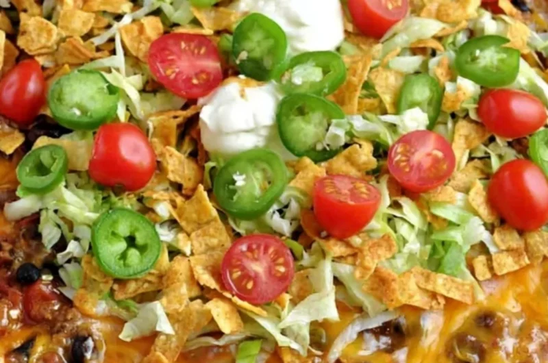 A delicious Walking Taco Casserole topped with cheese, lettuce, and tomatoes.