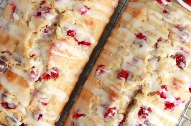 Freshly baked cranberry orange bread loaf with cranberries and orange slices