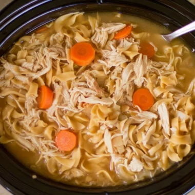 Bowl of high protein chicken noodle soup with fresh vegetables and herbs