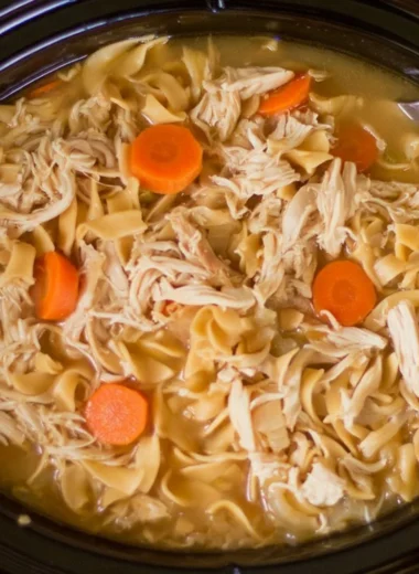 Bowl of high protein chicken noodle soup with fresh vegetables and herbs