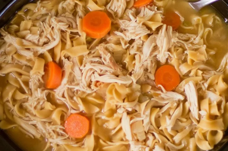 Bowl of high protein chicken noodle soup with fresh vegetables and herbs